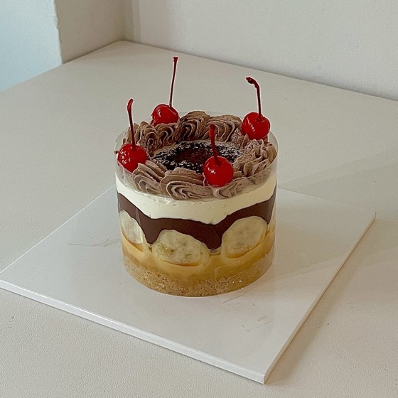 バナナとチョコレートを層にしてチェリーをのせたケーキ